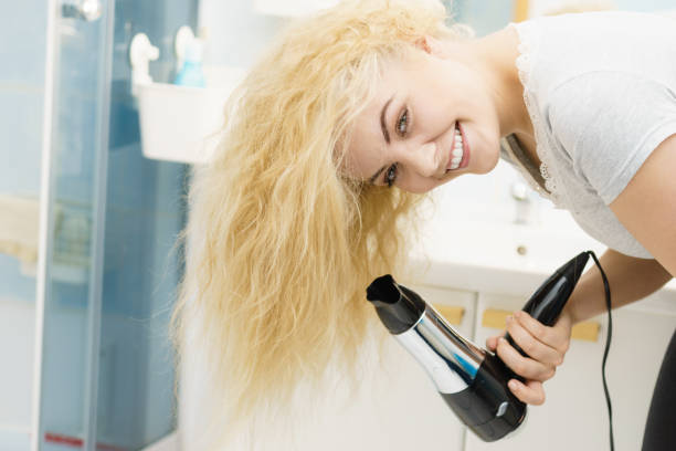 istock Blonde woman using hair dryer 2155599537