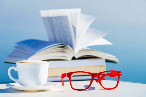 Reading on vacation. Coffee cup, book and red glasses against blue sea water. Relaxation on holidays trip. Mental health break.
