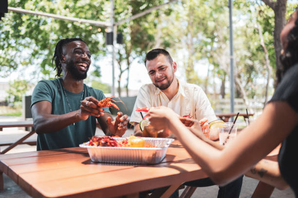 Friends enjoying crawfish outdoors at a picnic table in restaurant