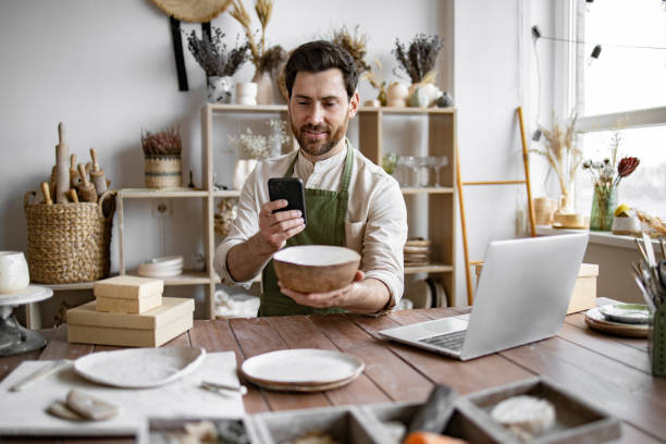 istock Successful guy store employee with ceramic tableware shoots photos. 2155605371