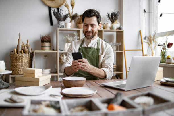successful guy store employee with ceramic tableware shoots photos. - detailhandel beroep fotos stockfoto's en -beelden