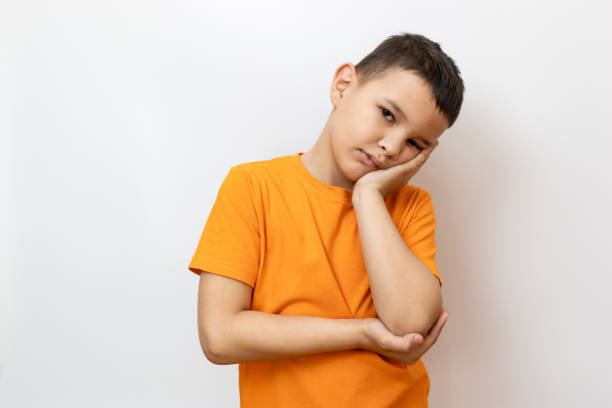 istock A guy in an orange T-shirt against a white background sadly supported his cheek with his palm. 2155605621