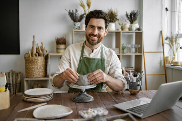 istock Male artist shaping clay pot in rustic studio filled with pottery tools 2155607497