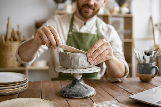 istock Smiling man working in a home pottery studio with laptop 2155607506
