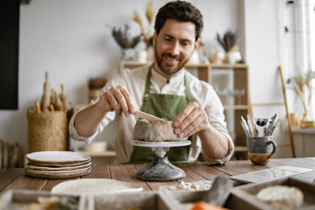 istock Smiling man working in a home pottery studio with laptop 2155607507
