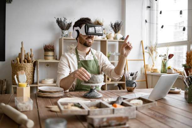 istock Man sculpting clay vase with VR headset in pottery studio 2155607526