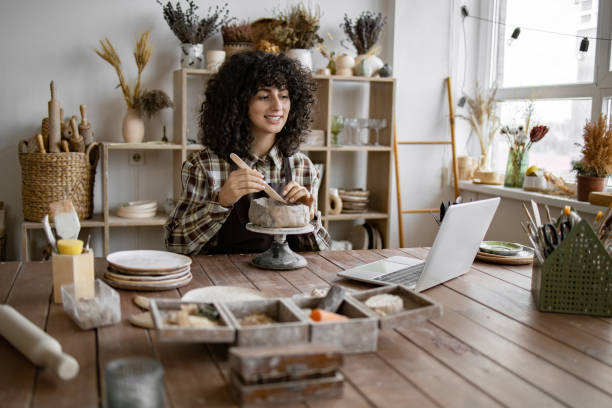 istock Smiling woman sculpting pottery while video chatting in studio 2155607560