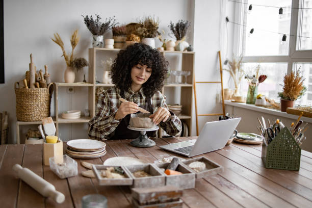 istock Woman crafting pottery in home studio with laptop 2155607564