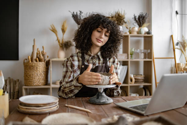 istock Female artist creating pottery in studio with laptop on table 2155607567