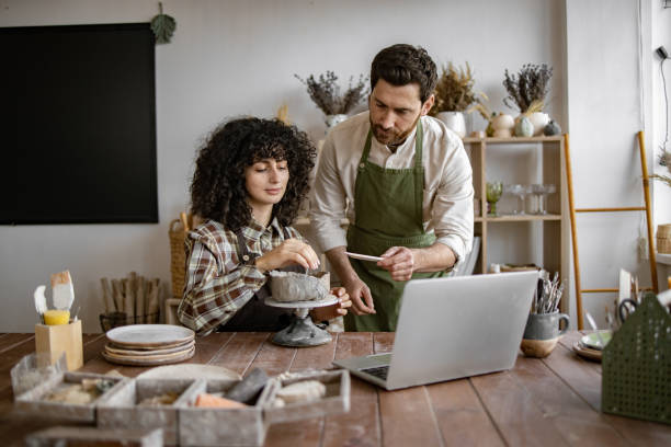 istock Man teaching woman pottery in studio with laptop 2155607569
