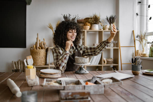 istock Female potter recording vlog while working in cozy pottery studio 2155607580