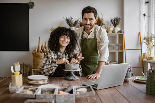 istock Happy couple creating pottery art in studio with laptop 2155607584