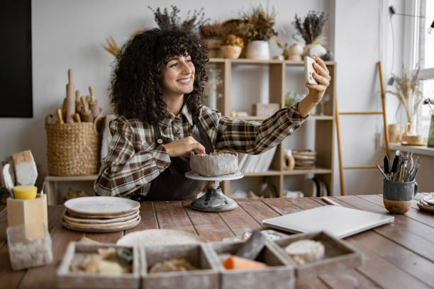 istock Woman potter taking selfie while sculpting pottery in art studio 2155607587