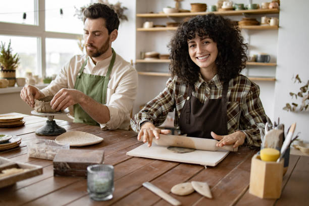 istock Couple sculpting clay together in pottery workshop 2155607591