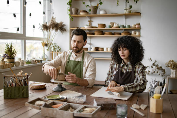 istock Bearded man and woman sculpting clay during pottery class 2155607596