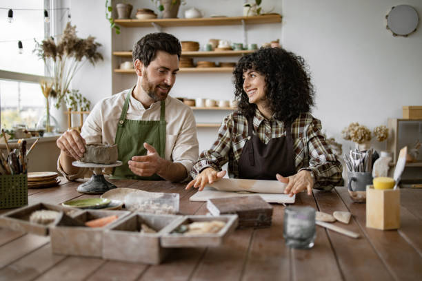 istock Mature man and woman sculpting clay together in pottery workshop 2155607601