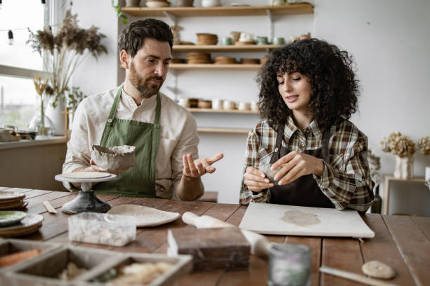 istock Bearded mature man and woman sculpting clay in pottery studio 2155607624