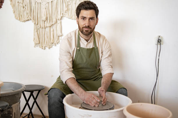 istock Male potter sculpting ceramic dishes in a pottery studio 2155610075