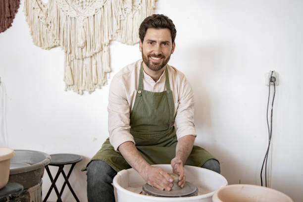 istock Male potter sculpting ceramic dishes on potter's wheel 2155610077