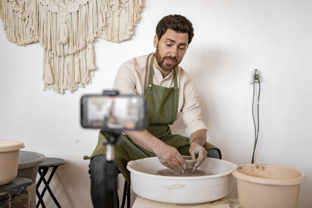 istock Young adult man creating pottery while recording video blog 2155610082