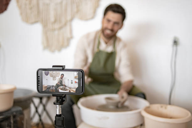 istock Young male potter recording video blog while sculpting pottery 2155610091