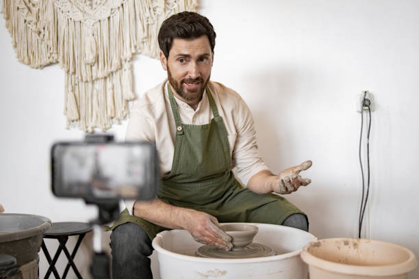 istock Potter recording video blog while sculpting a vase on potter's wheel 2155610094