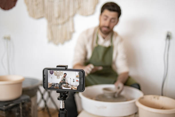 istock Young male potter recording video blog while sculpting vase 2155610097