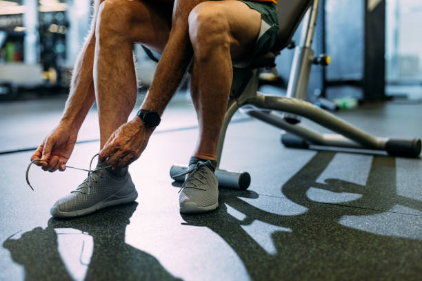 istock Man Tying Shoe Laces at Gym Before Workout Session 2155615559