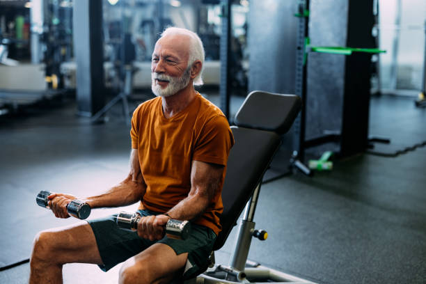 istock Senior Man Exercising with Dumbbells at the Gym 2155616063
