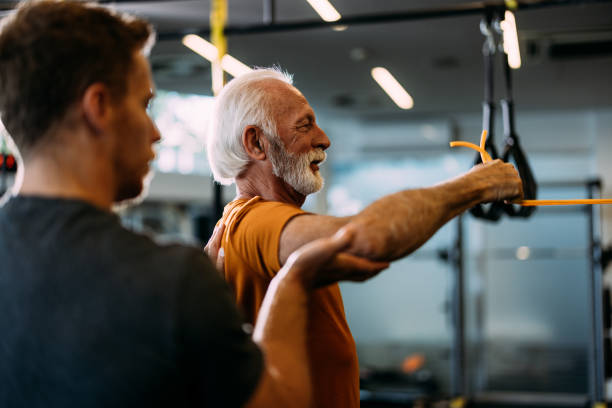 Senior Man Training With Personal Trainer in Gym