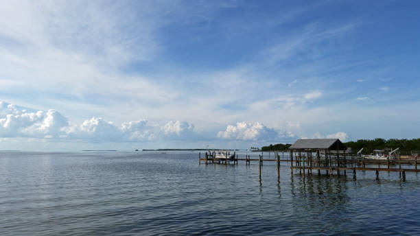 Docks and boats under summer cloudscape at sunset reflected in calm water of Florida Bay.
