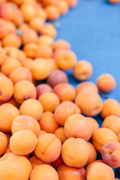 many fresh apricots on a tray on a bazaar counter