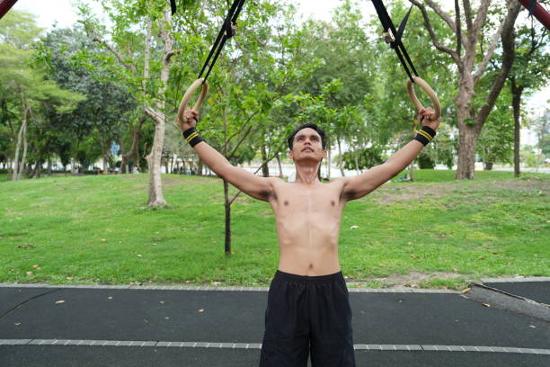 A fit Black athlete stretching his arms during a workout in a gym. Smiling male fitness trainer warming up, showing strength, health, and active lifestyle. Keywords: fitness, gym, stretching, athlete, workout, warm-up, trainer, active lifestyle, strong male model.