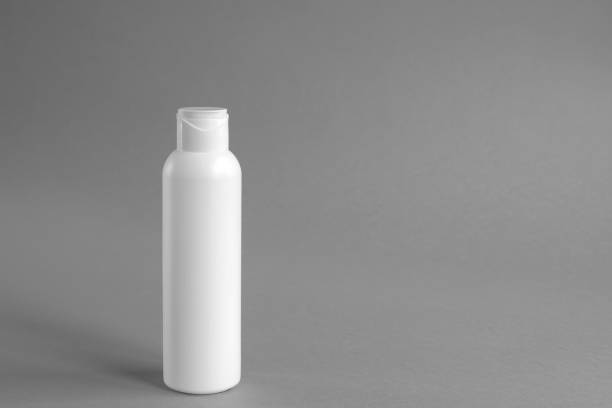 White plastic cosmetic lotion bottle mock-up with cap on gray background. Hygiene, Beauty and body skin care concept. Copy space.