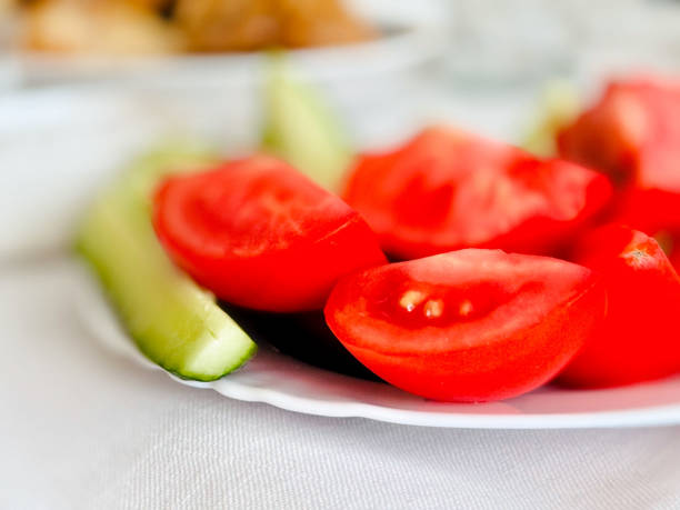 A close-up image showcasing fresh, juicy tomato slices and crisp cucumber spears artfully arranged on a white plate.