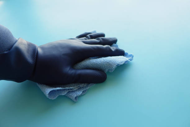 hand in blue rubber gloves cleaning table with towel .