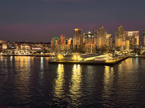 San Diego, CA -- January 30, 2024: San Diego skyline at sunset from San Diego Bay. The Star of India sailing ship can be seen at the dock.