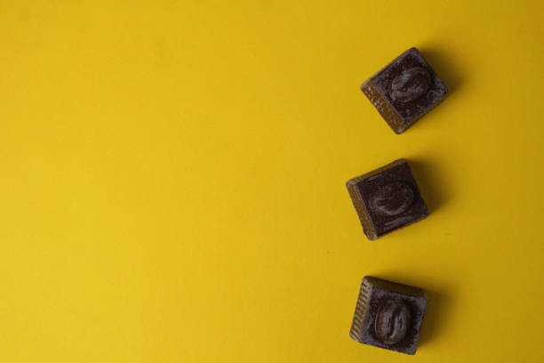 Chocolates lie in a row top view on a yellow background with space for copy space text.