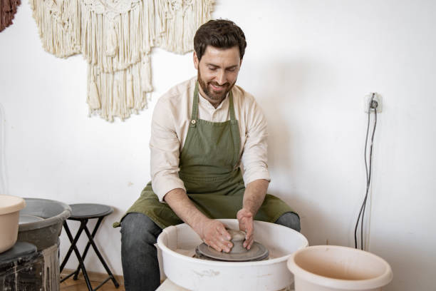 istock Male potter shaping clay on potters wheel in creative studio 2155657873