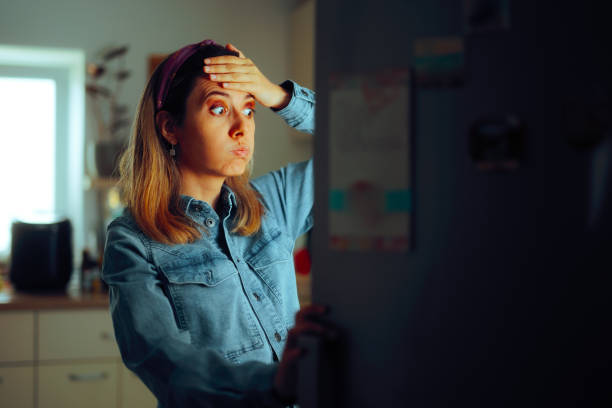 Woman looking Puzzled into the Fridge Wondering What to Eat