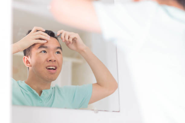 istock A teen boy is combing his hair while looking at himself in the mirror 2155659842