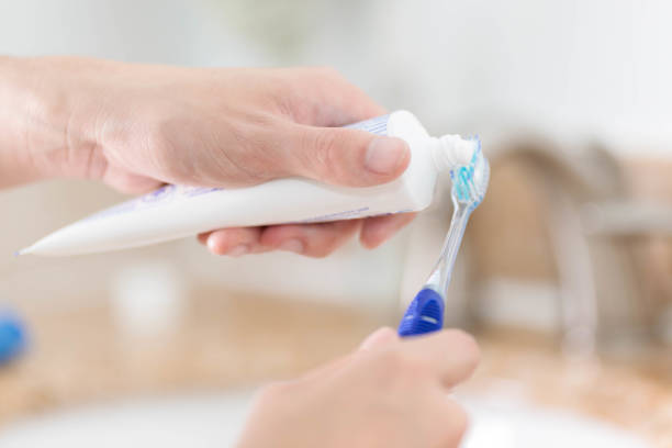istock Squirting toothpaste onto a toothbrush over the bathroom sink 2155659934