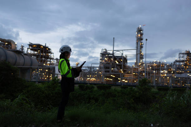 a man worker engineer conducts a site inspection at an industrial facility of gas and oil petroleum industry with utilizing a tablet for data management. technology and safety in maintaining operation