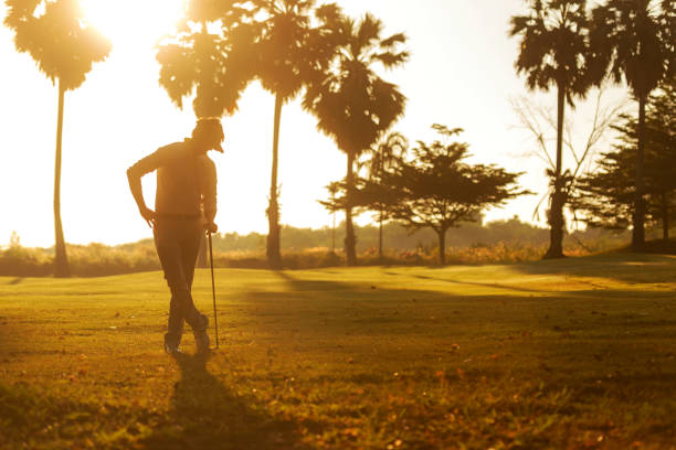 Silhouette Professional Golfer asian man swing and hitting golf ball practice at golf driving range and fairway in sunny morning day on club golf. Lifestyle and Sport Concept