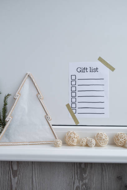 istock Holiday preparation paper note with GIFT LIST checklist text. Vision board wall with cozy minimalistic handmade new year Christmas decor Low key festive celebration 2155668555