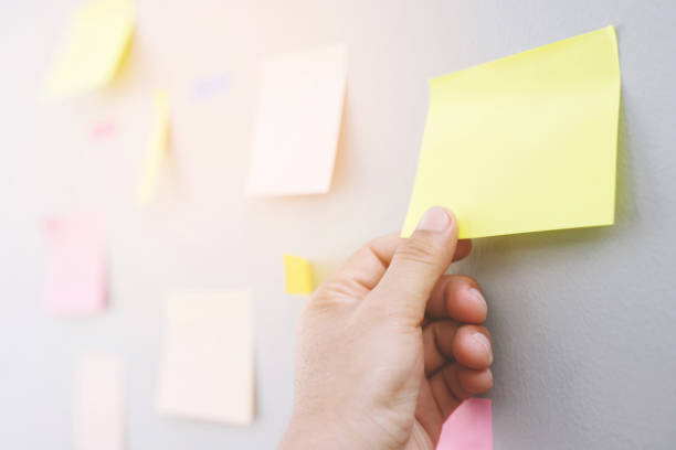 istock close up hand people business man  notes pad in the wall at meeting room. Sticky post note paper reminder schedule board. Colorful variety copy empty space. soft focus. 2155672543