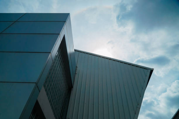 A building with a roof that has a rainbow on it. The sky is cloudy and the sun is shining through the clouds