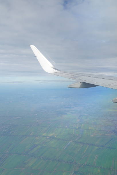 istock A white airplane wing is flying over a green field 2155678078
