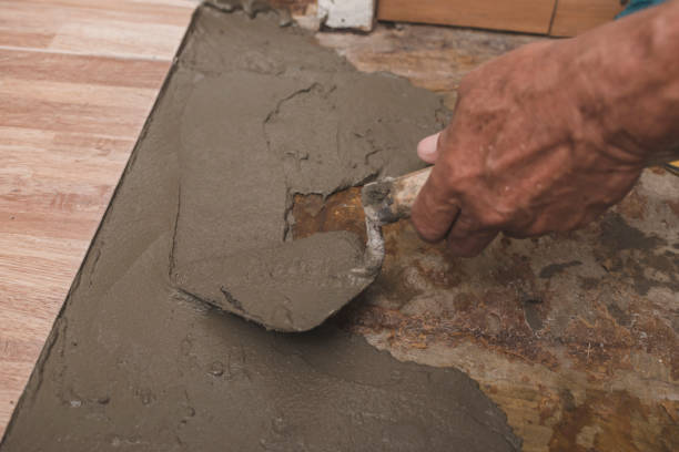 istock Adding concrete grout with a trowel on top of a bare floor. Adding new faux wood printed ceramic tiles at a hallway. Home renovation concept. 2155679557
