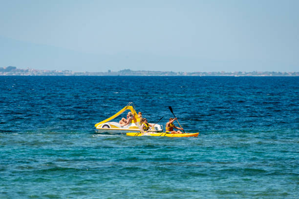 Tourists enjoying paddle boat and kayaking at Gerakini beach. Halkidiki, Greece, Europe.